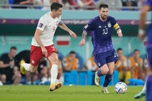 Robert Lewandowski persigue a Lionel Messi, en una jugada en el centro del campo en el partido entre Argentina y Polonia.