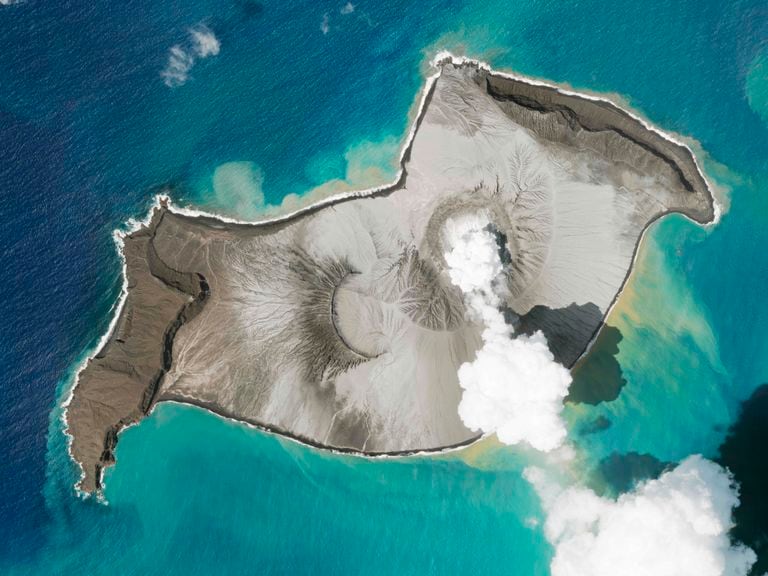In this satellite photo taken by Planet Labs PBC, an island created by the underwater Hunga Tonga Hunga Ha'apai volcano is seen smoking Jan. 7, 2022. An undersea volcano erupted in spectacular fashion near the Pacific nation of Tonga on Saturday, Jan. 15, sending large tsunami waves crashing across the shore and people rushing to higher ground. A tsunami advisory was in effect for Hawaii, Alaska and the U.S. Pacific coast, with reports of waves pushing boats up in the docks in Hawaii. (Planet Labs PBC via AP)