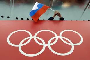 ARCHIVO - Una bandera rusa es desplegada encima de los anillos olímpicos durante los Juegos de Invierno en Sochi, Rusia, el 18 de febrero de 2014. (AP Foto/David J. Phillip)