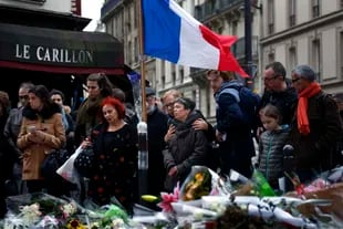 En esta imagen del 16 de noviembre de 2015, personas reunidas frente a la cafetería Le Carillon, zona de los atentados que habían tenido lugar tres días antes