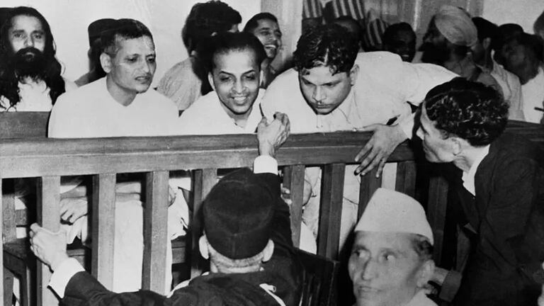Some of the defendants speak with their defense attorneys before their trial for Gandhi's assassination;  from left to right are Nathuram Vinayak Godse, Narayan Dattatraya Apte, Vishnu Rama Krishna and the bearded man in the second row is M. Badge