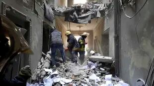 Esta foto difundida por el Servicio de Emergencia de Ucrania muestra al personal del servicio de emergencia inspeccionando los daños dentro del edificio del Ayuntamiento en Kharkiv, Ucrania, el martes 1 de marzo de 2022.