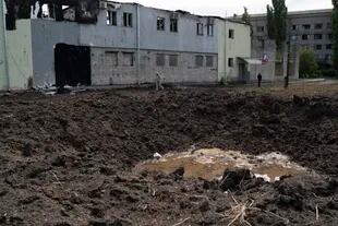 Two people walk through a crater created by a Russian attack near the Ukrainian Red Cross in Sloviansk, Ukraine, Monday, Sept. 5, 2022.  (AP Photo/Leo Correa)