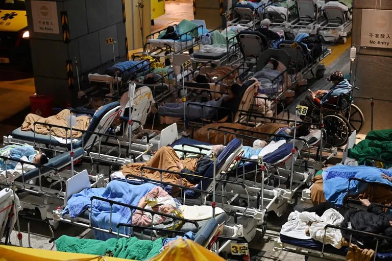 TOPSHOT - Las personas yacen en camas de hospital con temperaturas que bajan durante la noche fuera del Centro Médico Caritas en Hong Kong el 16 de febrero de 2022, mientras los hospitales se abruman con la ciudad que enfrenta su peor ola de coronavirus Covid-19 hasta la fecha. (Photo by Peter PARKS / AFP)