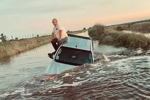 El productor Armando Rey sobre el techo de su camioneta, tapada por el agua en un camino rural que une Buenos Aires con Santa Fe