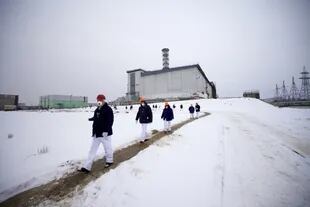Trabajadores y visitantes caminando con ropa protectora en los terrenos de la planta de energía nuclear de Chernobyl en Ucrania