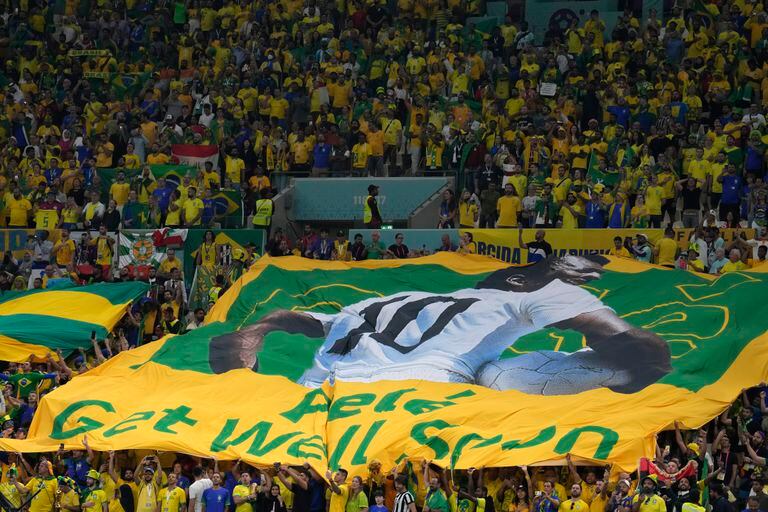 Fanáticos brasileños extienden una bandera brasileña gigante con la imagen del ex astro brasileño Pelé 