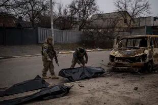 Soldados ucranianos recuperan los restos de cuatro civiles de un vehículo calcinado en Bucha, a las afueras de Kiev, Ucrania