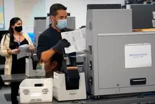 Un trabajador electoral carga las boletas en una máquina de escaneo en la Junta Electoral del condado de Miami-Dade