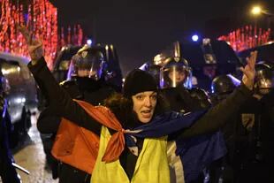 Una manifestante con chaleco amarillo en los Campos Elíseos durante las celebraciones de Año Nuevo, con la policía detrás