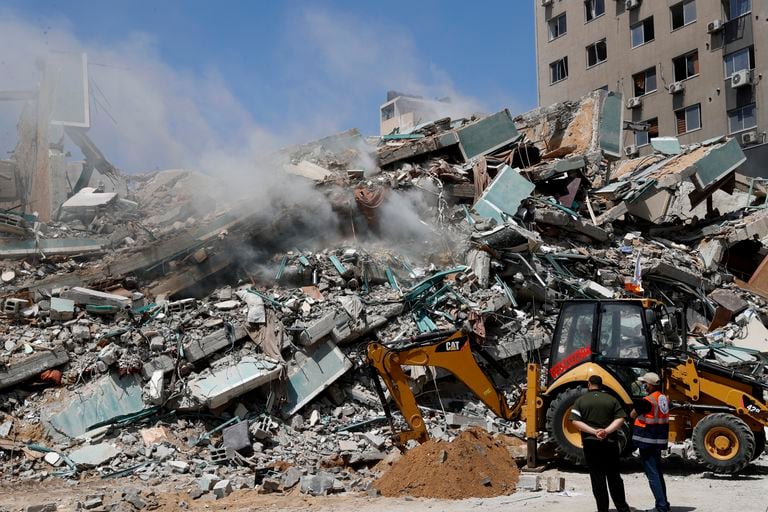 Trabajadores despejan los escombros de un edificio que fue destruido por un ataque aéreo israelí el sábado; albergaba las oficinas de las organizaciones de noticias Associated Press, Al-Jazeera y otras en Ciudad de Gaza, el domingo 16 de mayo de 2021. (AP Foto/Adel Hana)