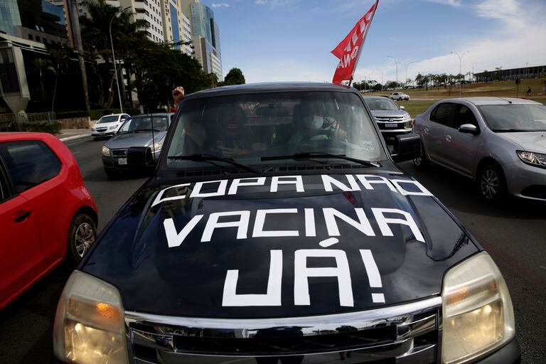 Personas en un auto protestan en Brasilia contra la realización de la Copa América en Brasil debido a la pandemia de coronavirus. La pancarta dice en portugués “Copa no, vacunas ya”. (AP Foto/Eraldo Peres)