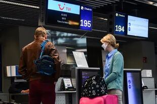 Los pasajeros se detienen en el check-in para su vuelo a Mallorca en el aeropuerto de Duesseldorf, Alemania occidental, el 15 de junio de 2020
