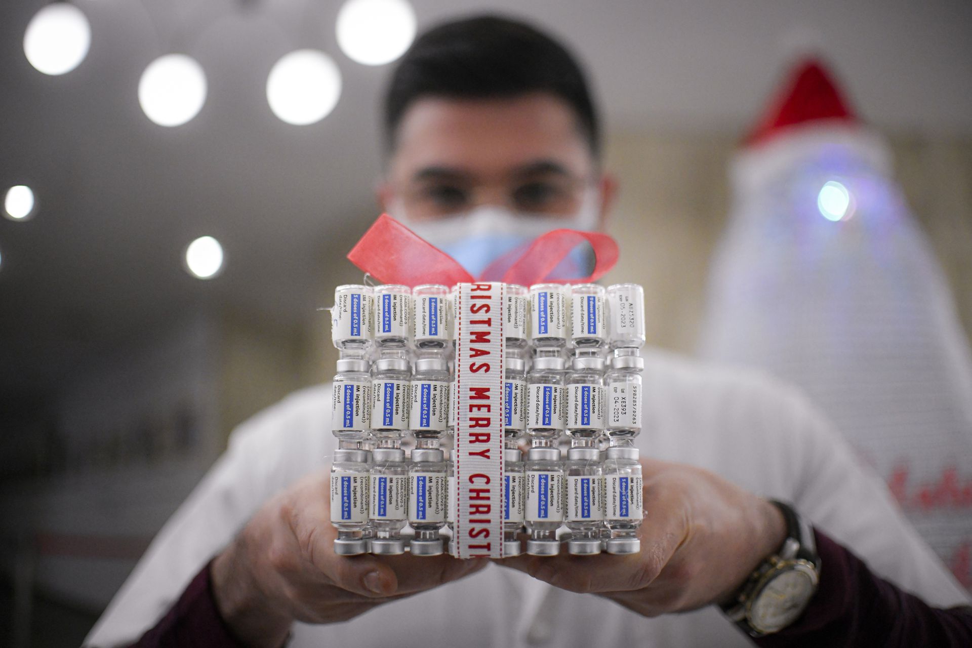 Un miembro del personal médico de un centro de vacunación COVID-19, sostiene una caja de regalo confeccionada con frascos vacíos de vacunas