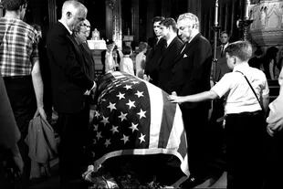 Un chico toca el féretro de Kennedy durante su funeral en la catedral de San Patricio en Nueva York