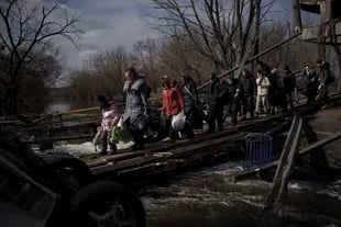 Ukrainians cross an improvised path under a destroyed bridge while fleeing Irpin, on the outskirts of Kyiv, Ukraine, Wednesday, March 9, 2022. (AP Photo/Felipe Dana)