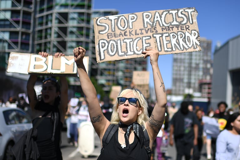 Los manifestantes llevan pancartas con lemas mientras marchan en la carretera frente a la embajada de Estados Unidos en Londres el 31 de mayo de 2020