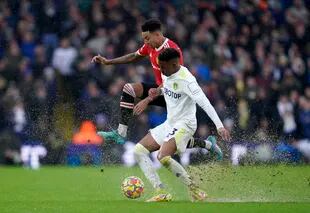 Junior Firpo, de Leeds United, al frente, pelea por el balón con Jesse Lindgard, del Manchester United, entre la lluvia y el viento