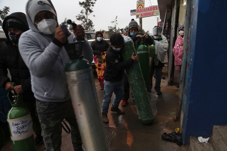 Un grupo de personas espera frente a un depósito para recargar sus tubos de oxígeno, en el barrio San Juan, en Lima