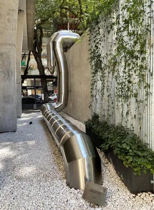 La escultura metálica avanza desde la entrada, se interna bajo el deck que rodea la pileta y vuelve a salir a la superficie frente a la ventana del gimnasio