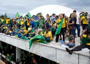 Manifestantes, simpatizantes del expresidente brasileño Jair Bolsonaro, en el techo del edificio del Congreso Nacional después de irrumpir en el recinto, el domingo 8 de enero de 2023, en Brasilia. 