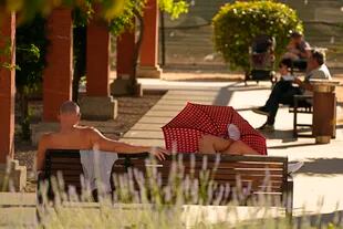 Dos hombres se relajan en un parque en una calurosa tarde en Madrid, España, el martes 7 de junio de 2022