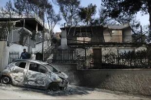 Un hombre frente a su auto y hogar devastados por las llamas
