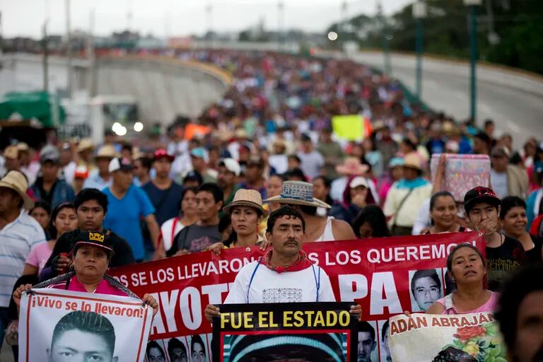 ARCHIVO - Familiares de los 43 estudiantes de la escuela de maestros de Ayotzinapa que desaparecieron encabezan una marcha por el primer aniversario de las desapariciones de los estudiantes en Chilpancingo, México, el sábado 26 de septiembre de 2015. Expertos de la Comisión Interamericana de Derechos Humanos presentaron un informe el lunes 28 de marzo de 2022 que dice que la Armada de México también fue parte del encubrimiento de la desaparición en 2014. (AP Foto/Rebecca Blackwell, Archivo)