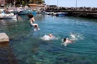 Lo niños juegan en el agua en el pueblo pesquero de San Giovanni li Cuti, cerca de Catania
