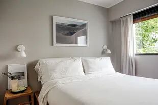 En el dormitorio, cama de petiribí con cajones integrados, lámparas ‘Uncuerno’ (A3), fotos (Lucía María Ledesma), banco (El Paso Estudio) y jarra (Tortuga).