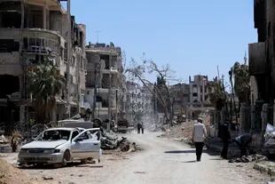 En esta imagen de archivo, sitios caminan por la destruida localidad de Douma, el escenario de un presunto ataque con armas químicas, cerca de Damasco, Siria