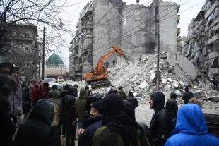 Las personas observan cómo los equipos de rescate buscan sobrevivientes bajo los escombros de un edificio derrumbado