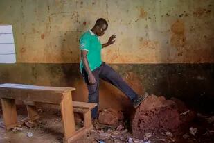 El maestro Emmy Odillo patea un hormiguero que se formó en un rincón de un aula en la Escuela Primaria Mawero, a las afueras de la localidad de Busia, el martes 19 de octubre de 2021, en el este de Uganda. (AP Foto/Nicholas Bamulanzeki)