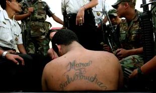 A gang member of the Mara Salvatrucha gang is detained by army and police in Guatemala City, July 20, 2005. A string of violent and mysterious killings targeting gang members and criminals in Guatemala has prompted rumors of a "social cleansing," an effort to weed out undesirable members of society. Some blame police, others point a finger at vigilante groups sick of rising crime. Police say rival gangs are responsible. (AP Photo/Rodrigo Abd)