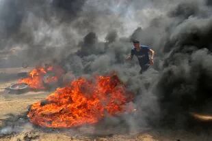 Un palestino camina a través del humo de los neumáticos quemados durante las protestas
