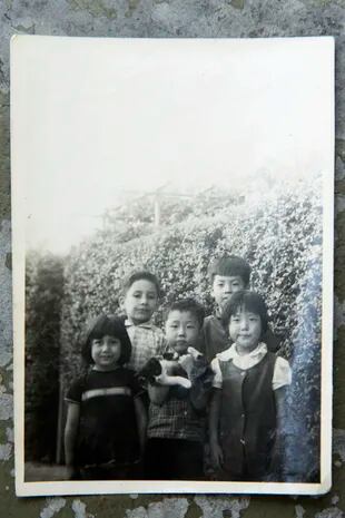 Chang Sung Kim (detrás y a la derecha), en la casa del barrio Rivadavia en la que su familia se instaló. A su lado, una de sus hermanas, vecinos y amigos de la colectividad.