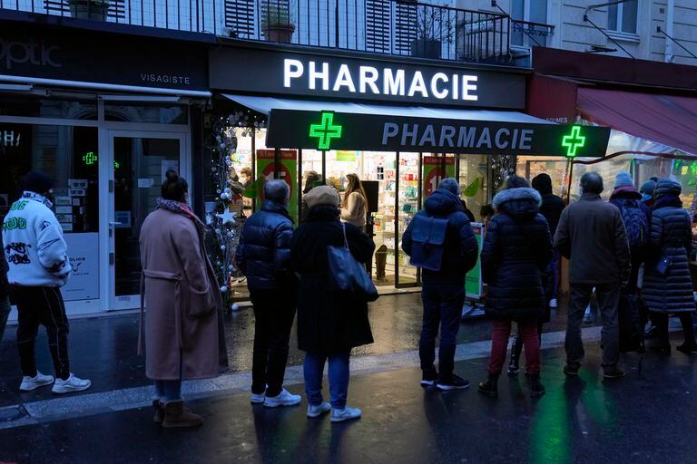 Gente esperando ante una farmacia abierta el domingo para conseguir pruebas diagnósticas de COVID-19, en París, Francia, el domingo 9 de enero de 2022. (AP Foto/Francois Mori)