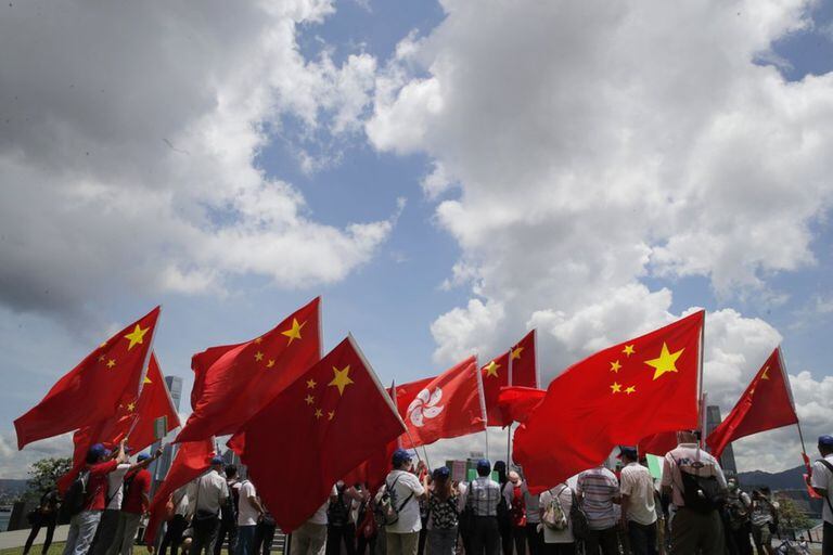 Partidarios del gobierno chino sostienen banderas de China y Hong Kong durante una manifestación en Hong Kong para celebrar la aprobación de la ley