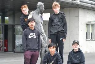 Chicos posan con la estatua de Albert Gudmundsson, primer jugador que emigró de Islandia
