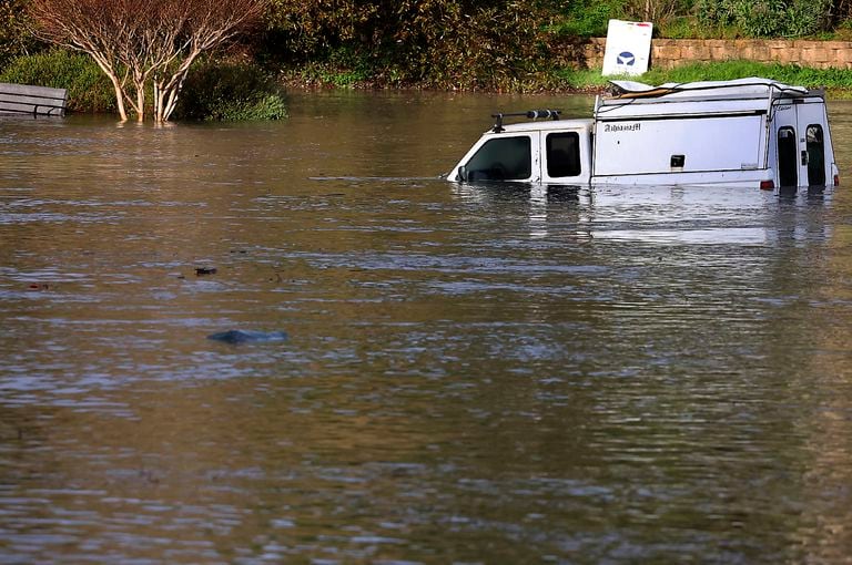 A pickup truck is partially submerged in Santa Cruz, Calif., early Saturday, Jan. 15, 2022, as the surge from a tsunami created by an underwater volcano near Tonga inundated a parking lot at the Upper Harbor. Moments later all the water receded from the lot before flooding it again shortly thereafter. (Shmuel Thaler/The Santa Cruz Sentinel via AP)