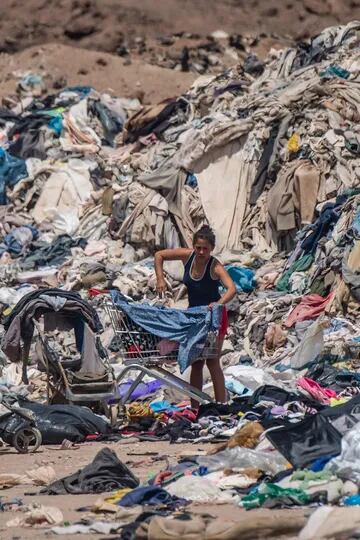 Una mujer busca ropa entre las toneladas de ropa desechada 
