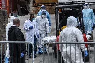 Los trabajadores médicos llevan un cuerpo a un camión refrigerado afuera del Hospital de Brooklyn el 31 de marzo de 2020 en la ciudad de Nueva York. Debido a un aumento en las muertes causadas por el Coronavirus, los hospitales están utilizando camiones refrigerados como morgues de turno.