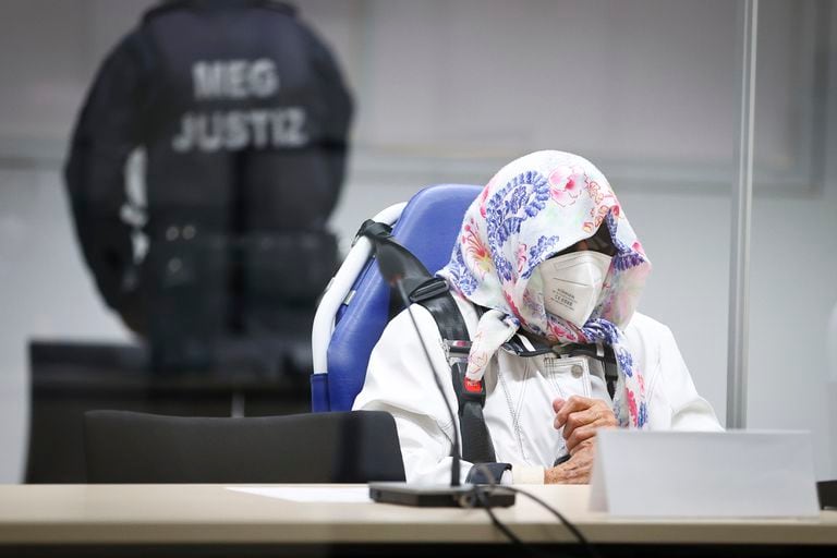La acusada Irmgard Furchner, de 96 años, aparece sentada en una silla de ambulancia detrás de una ventana de plexiglás en el tribunal de Itzehoe, Alemania, martes 19 de octubre de 2021