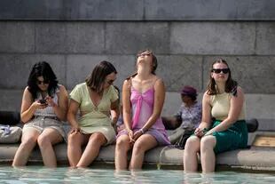 Un gruppo di donne immerge i piedi alla fontana di Trafalgar Square nel centro di Londra il 18 luglio 2022.
