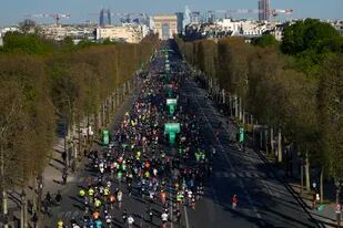 Los corredores pasan por los Campos Elíseos al inicio del Maratón de París, el domingo 3 de abril de 2022. (AP Foto/Francois Mori)