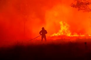 En esta imagen, proporcionada por la brigada antiincendios SDIS33, se muestra a un bombero luchando contra las llamas en un incendio cerca de la localidad de Saumos, en el suroeste de Francia, el 13 de septiembre de 2022. (SDIS33 vía AP)