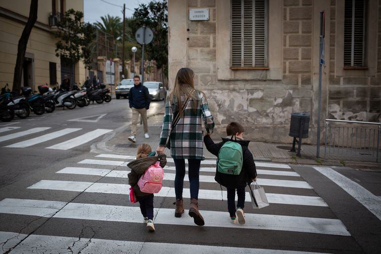 Una mujer acompaña a dos niñas a la escuela el primer día del semestre posterior al final de las vacaciones de Navidad, el 10 de enero de 2022 en Barcelona, España