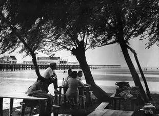 8 de diciembre de 1957: una familia almuerza en el espigón del balneario, rodeada de sauces y tibias aguas.
