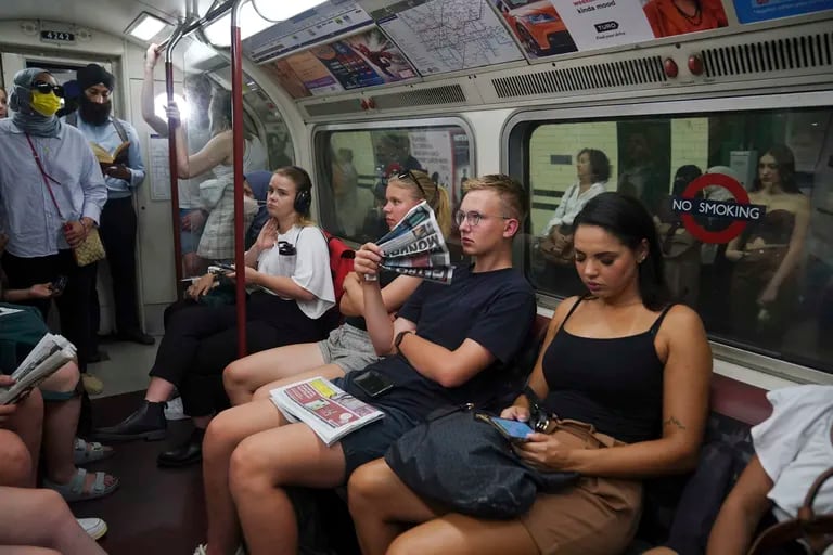 Un joven utiliza un periódico como abanico mientras viaja en la línea Bakerloo en el centro de Londres durante la ola de calor, el lunes 18 de julio de 2022. 