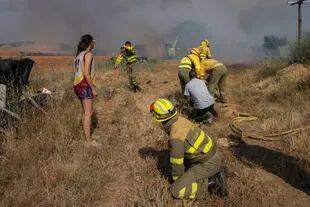 Personas trabajan para extinguir un incendio que se acerca a una casa en Tábara, noroeste de España